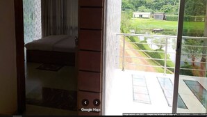 A room with a bed, a window, and a view of a green landscape. - Shalban Green Resort (Gazipur)