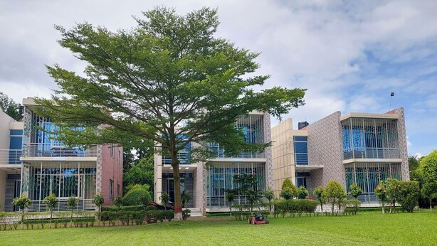 A modern building with multiple floors, large windows, and a well-maintained lawn in front. - Shalban Green Resort (Gazipur)