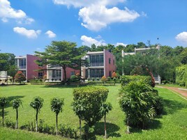 Um edifício moderno com fachada de vidro, rodeado por vegetação bem cuidada e um céu azul límpido.