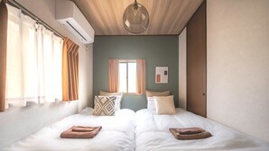 A room with two beds, a window, an air conditioning unit, and a hanging light fixture. - Closest whole house from Haneda Airport (Higashikojiya, Ota-ku)