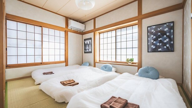 A traditional Japanese-style room with tatami flooring, two beds with white bedding, and large windows with grid patterns. - Closest whole house from Haneda Airport (Higashikojiya, Ota-ku)