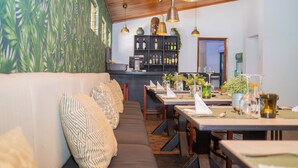Un restaurant doté d’un plafond en bois, d’un bar et d’un espace repas avec des tables et des chaises.
