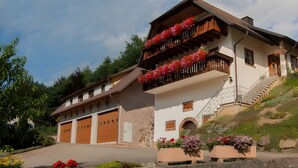Ein zweistöckiges Gebäude mit Balkon, Treppe und Garage.