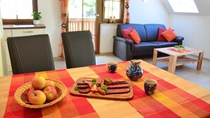 A dining table with a fruit basket, a charcuterie board, and two cups.