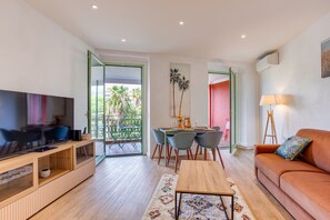 Ein modernes Wohnzimmer mit Flachbildfernseher, einer Holzunterhaltungsecke, einer Couch und einem Essbereich mit Tisch und Stühlen.