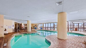 En inomhuspool med väggar av genomskinligt glas, ett tegelgolv och en skylt som förbjuder dykning.