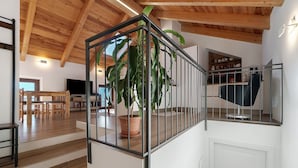 Una escalera con barandilla de metal, piso de madera, una planta en maceta y un televisor al fondo.