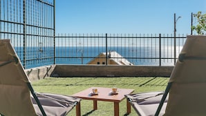 Una terraza con dos sillas, una mesa y vistas al mar.