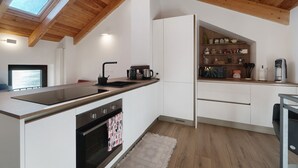 Una cocina moderna con tragaluz, armarios blancos y techo de madera.