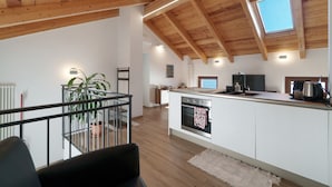 Una cocina moderna con una isla central, vigas de madera y un tragaluz.