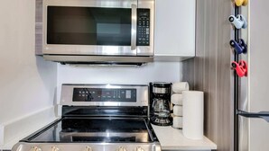 Une cuisine équipée d’un four à micro-ondes, d’une cuisinière et d’un réfrigérateur en acier inoxydable.