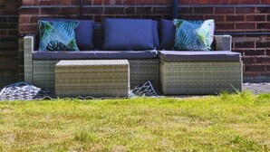 A wicker sofa with cushions against a brick wall. - Cosy 2BR House on Quiet Street (Nottingham)