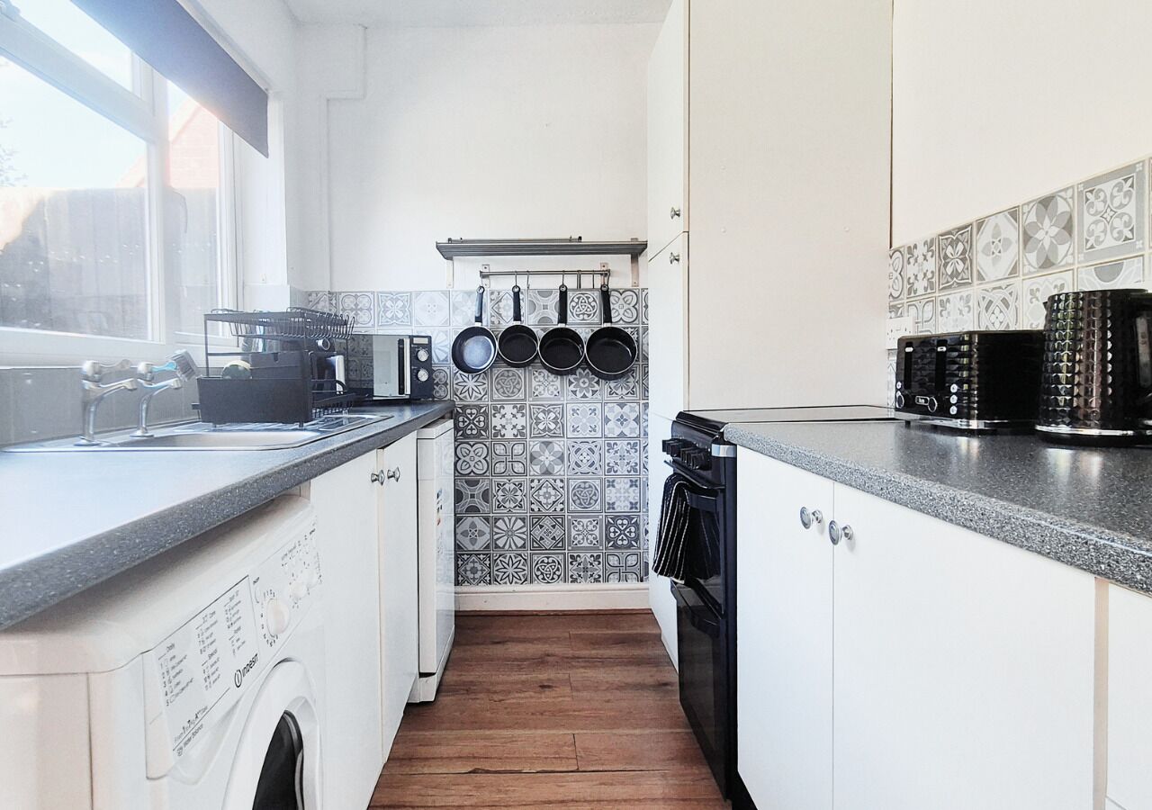 A compact kitchen with a washing machine, a microwave, and a stove.