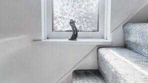 A window with a geometric patterned blind, a small black object on the sill, and a grey textured bench. - Cosy 2BR House on Quiet Street (Nottingham)