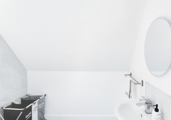 Une salle de bain moderne avec un lavabo blanc, un miroir et un porte-serviettes.