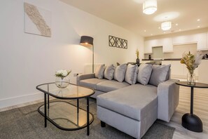 A modern living room with a grey sofa, a glass coffee table, and a black floor lamp. - Toast Stays - The Slate at Parsons House (Washington)