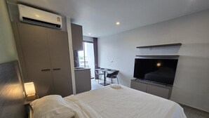 A hotel room with a bed, a TV, a desk, and a kitchenette. - Palm Bay Studio T3 -532 (Chalong)
