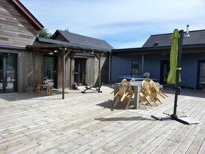 Une terrasse en bois équipée d’appareils de musculation, d’une table de billard et de sièges d’extérieur.