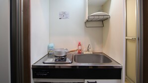A compact kitchenette with a stove, sink, and storage cabinet. - Small-Town Feel, Big-City Access | Homey Stay in Nakano (Nogata, Nakano-ku)