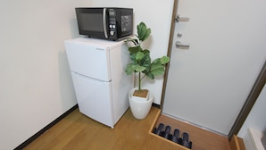 A compact kitchenette with a white refrigerator, a microwave, and a potted plant. - Small-Town Feel, Big-City Access | Homey Stay in Nakano (Nogata, Nakano-ku)