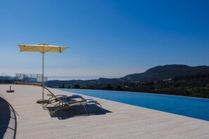 A poolside area with lounge chairs and a large umbrella, overlooking a scenic landscape with hills and a clear sky. - L´Oro di Pizzon - Frantoio Deluxe | Panoramic View (Pizzon)