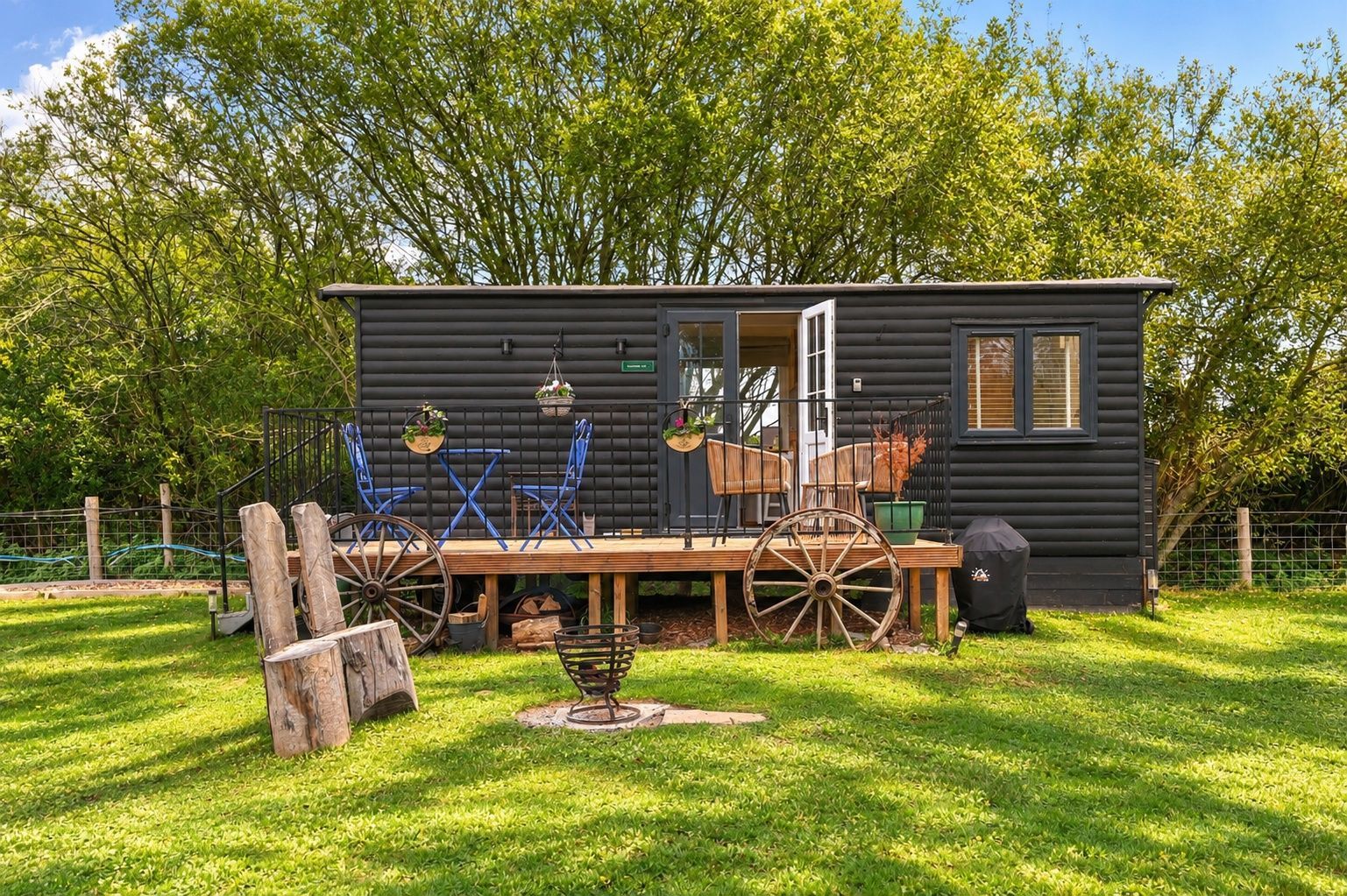 Eine Hütte mit einer Veranda, Sitzgelegenheiten im Freien und Grillplatz.