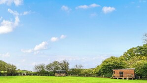 A rural property with three cabins, a fenced field, and trees in the background. - Badger Shepherds Hut -  a holiday let that sleeps 2 guests  in 1 bedroom (Hartfield)