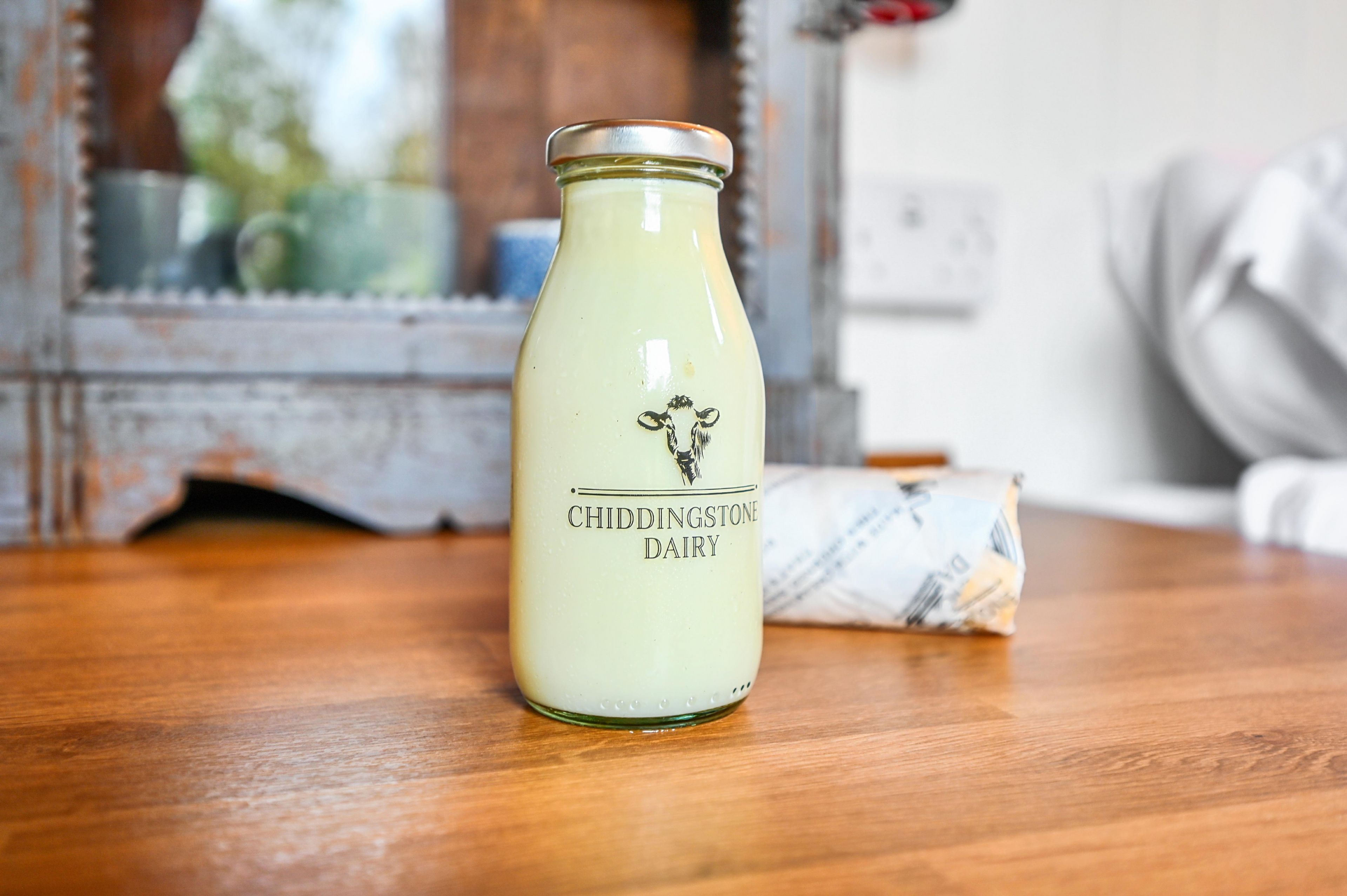 A bottle of Chiddington Dairy on a wooden surface with a blurred background.