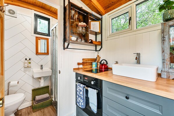 A compact kitchen with a built-in oven, a sink, and a window above the counter.