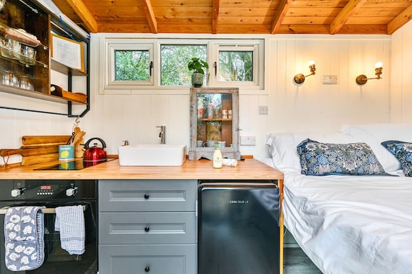 A compact bedroom with a bed, bedside table, and a window with a view of trees.