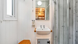 A bathroom with a white sink, wooden cabinet, and a mirror. - Stag Shepherds Hut -  a holiday let that sleeps 4 guests  in 1 bedroom (Hartfield)