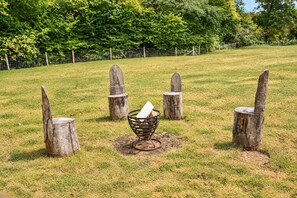 A grassy outdoor area with four wooden posts and a metal basket in the center. - Stag Shepherds Hut -  a holiday let that sleeps 4 guests  in 1 bedroom (Hartfield)
