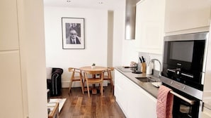 A modern kitchen with white cabinets, a stainless steel oven, and a wooden dining table.