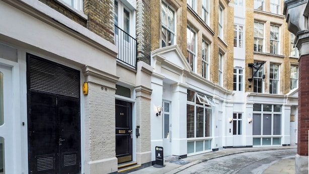 A row of traditional brick townhouses with white facades, large windows, and a curved driveway.