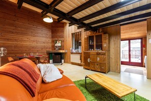 A cozy living room with a sofa, a wooden cabinet, and a dining area. - Villa 'La Cabane D'Ana' with Private Terrace, Private Garden and Wi-Fi (Bordeaux)