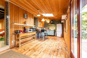 Un intérieur en bois comprenant un coin cuisine équipé d’un four à micro-ondes, d’une cuisinière et de tabourets de bar.