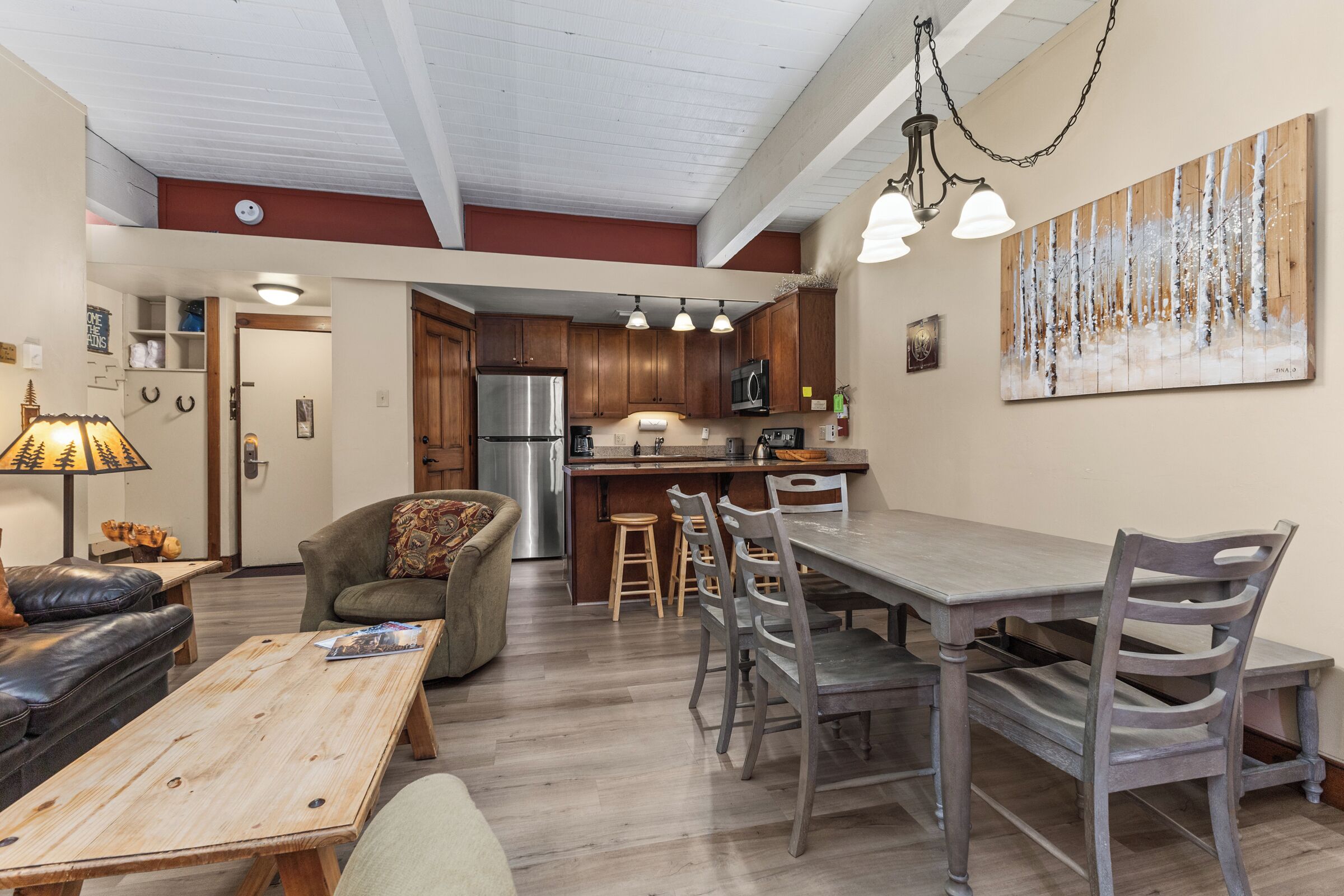 Una cucina moderna con mobili in legno, un frigorifero in acciaio inossidabile e un'area pranzo con tavolo e sedie di legno.