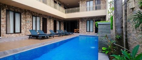 Um hotel com piscina, espreguiçadeiras e fachada de pedra.