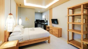 A modern bedroom with a wooden bed, bedside table, and a TV on a wooden stand. - Kris Residence Sanur (Denpasar)