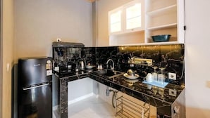 A compact kitchen with a black refrigerator, a coffee maker, and a sink. - Kris Residence Sanur (Denpasar)