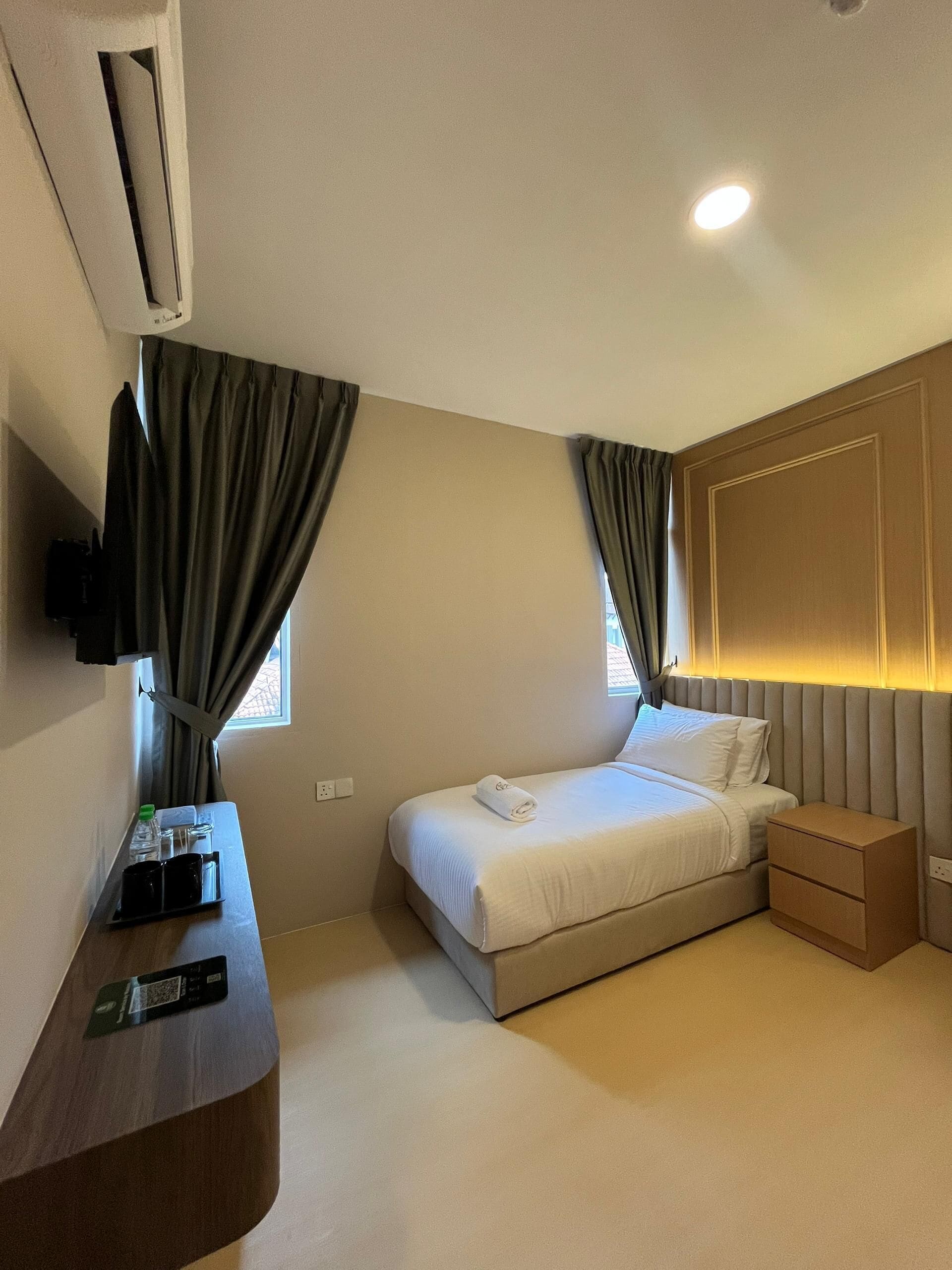 Une chambre d’hôtel avec un lit, des tables de chevet, une télévision et une fenêtre avec des rideaux.