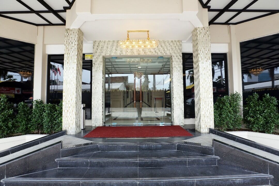 A hotel entrance with a red carpet, black marble steps, and a glass door.