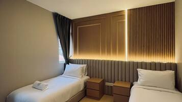 Une chambre d’hôtel avec deux lits, une table de chevet et une lampe fixée au mur.