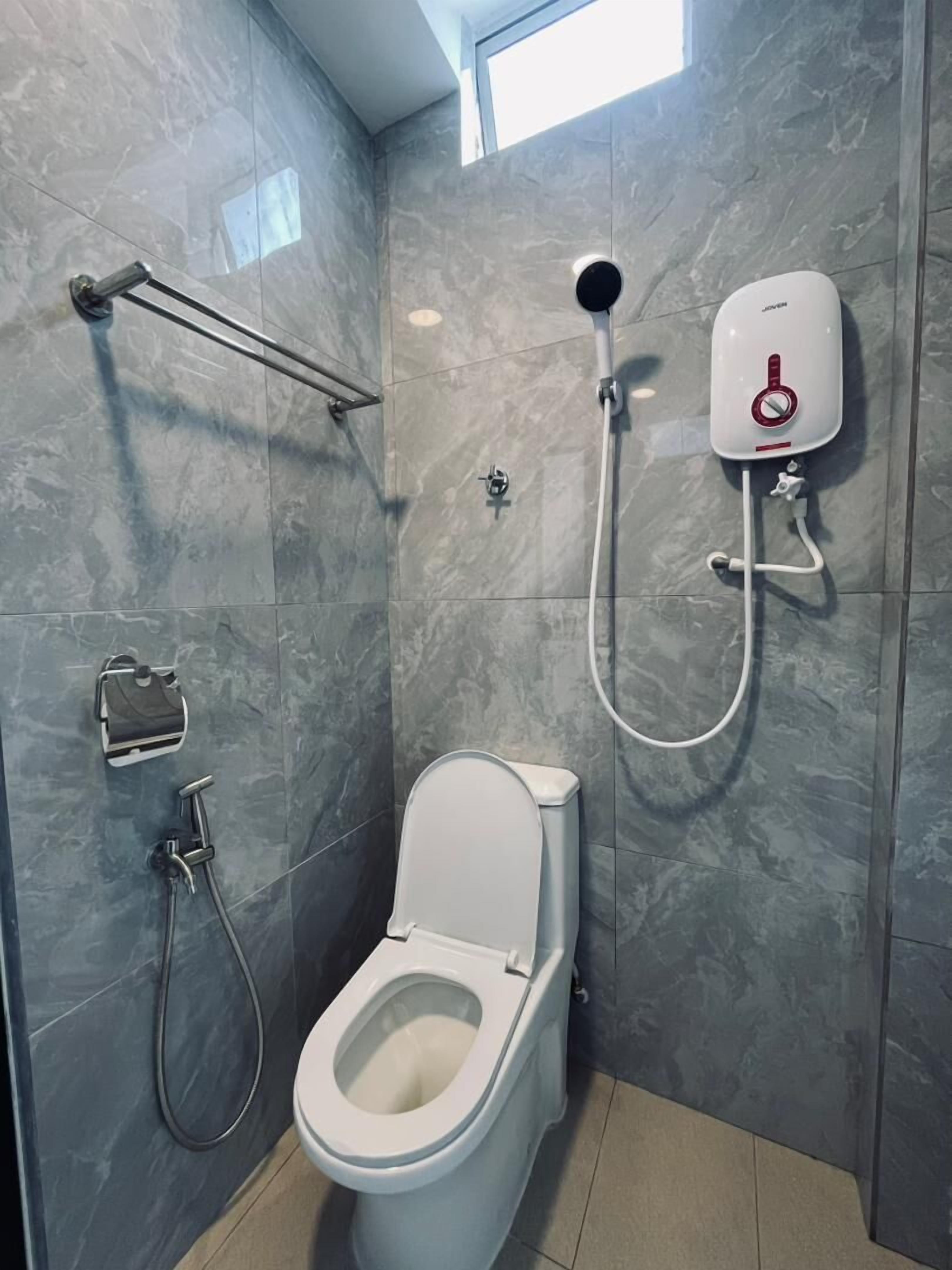 Uma casa de banho moderna com sanita, chuveiro manual e bidé fixado na parede.