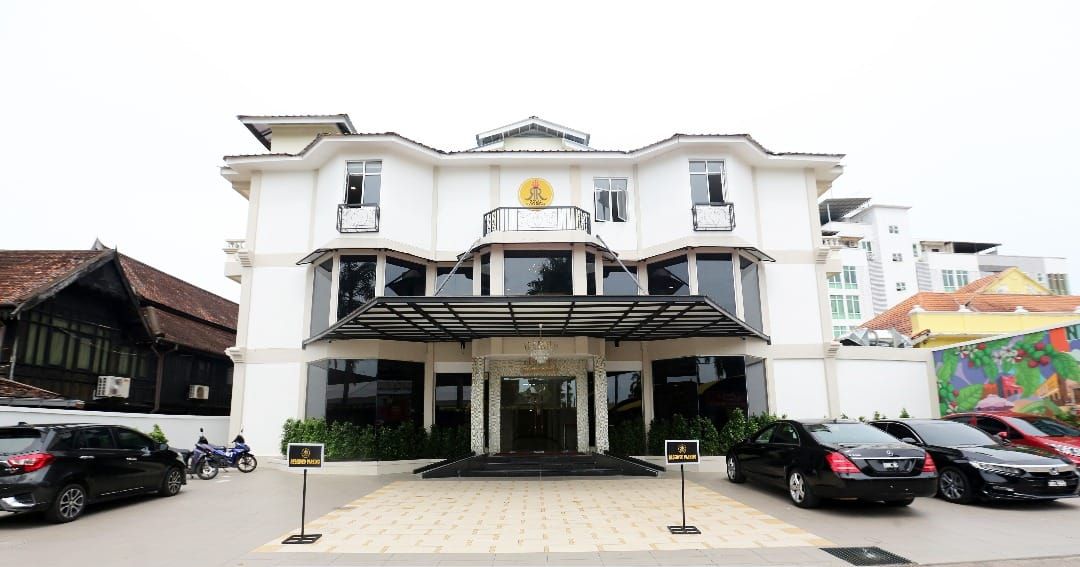 A two-story building with a central entrance, a covered walkway, and a sign indicating it is the Royal Guest House.