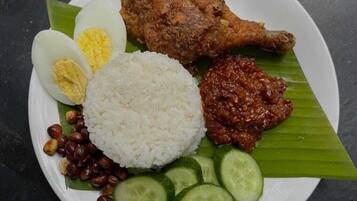 A plate of food with rice, boiled egg, fried chicken, sambal, peanuts, and cucumber slices.
