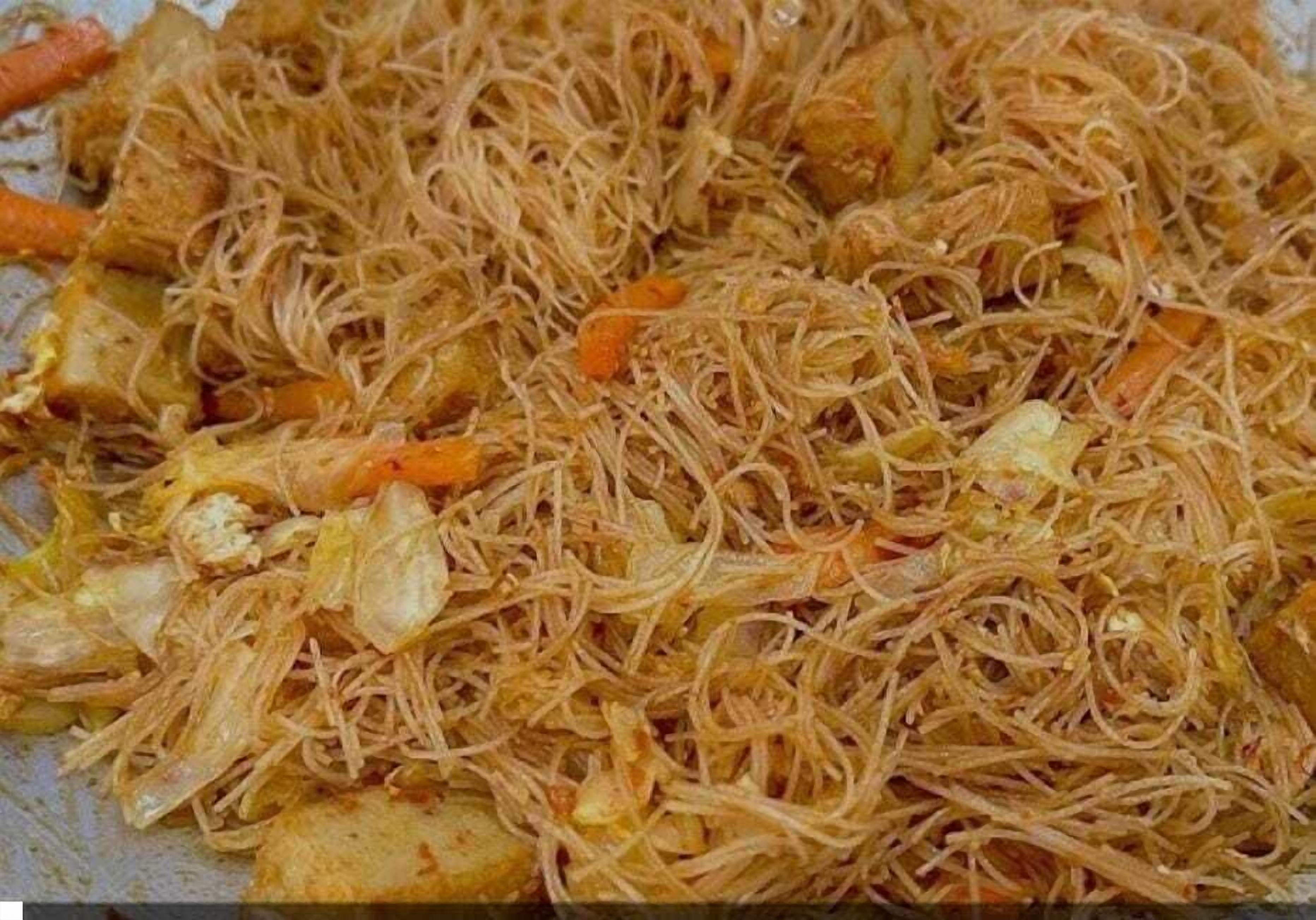 A close-up of a dish with noodles, vegetables, and possibly chicken.