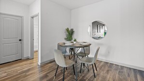 Een eetgedeelte met een ronde tafel, vier stoelen en een kleine plant in een pot.