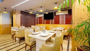 A restaurant with multiple tables and chairs, wooden paneling, and hanging lights. - The Grace b&B (New Delhi)
