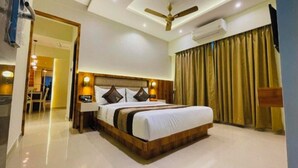 A modern hotel room with a large bed, a ceiling fan, an air conditioning unit, and a view of a hallway. - The Grace b&B (New Delhi)